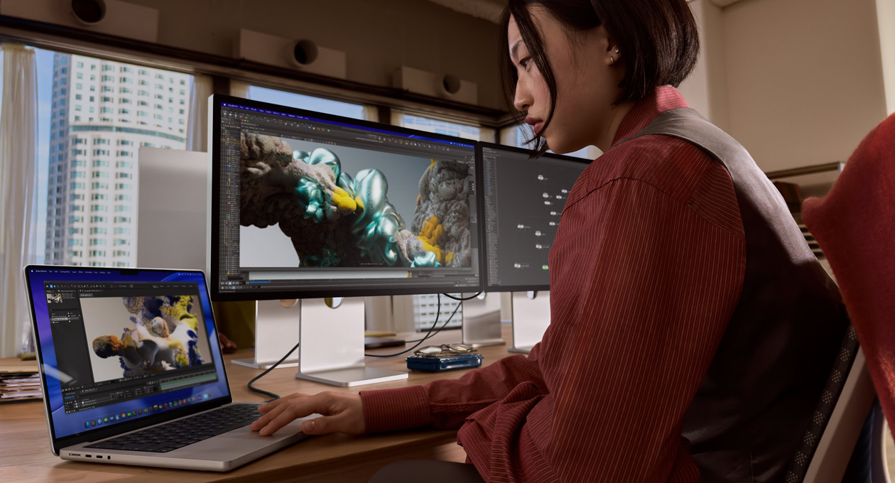 En person i kontorsmiljö arbetar på en MacBook som är ansluten till Studio Display XDR med en Thunderbolt 5-port