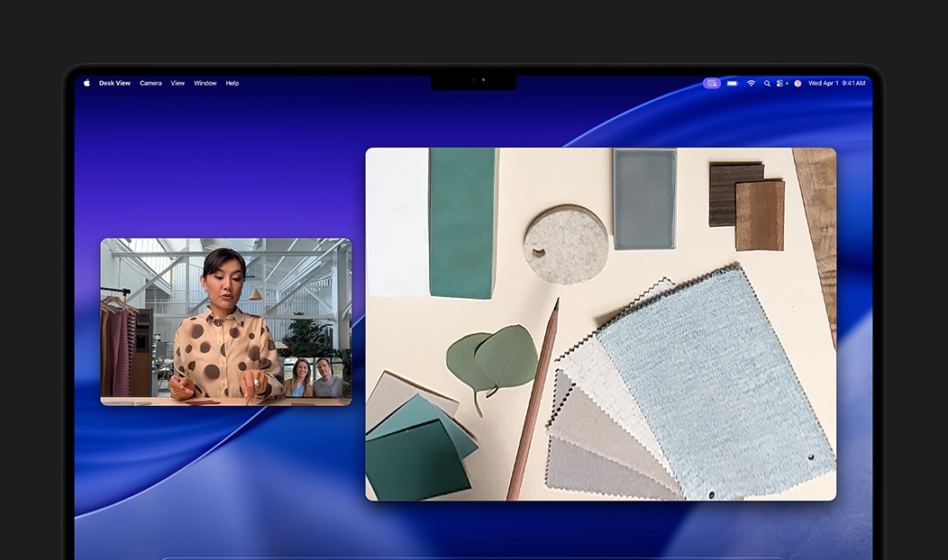 A video call on MacBook Pro of a person using the Desk View feature to show their workspace filled with fabric squares to two people on the call, Desk View lets them show their workspace and their face simultaneously