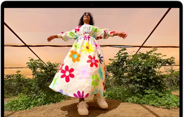 MacBook Air 螢幕顯示穿著色彩繽紛服裝的人像照片，展示 Liquid Retina 顯示器的色域和解像度