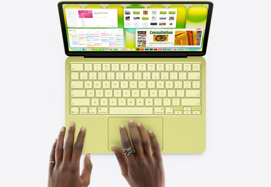 MacBook Neo citrusszínben, egy felhasználó keze gépelés és az érintőpad használata közben, a kijelzőn gyors egymásutánban váltják egymást különböző műveletek, köztük egy prezentáció összeállítása, fájlok kezelése, egy weboldal megnyitása és zenehallgatás, végül a felhasználó egyszerre megjeleníti az összes megnyitott ablakot a Mission Controllal.