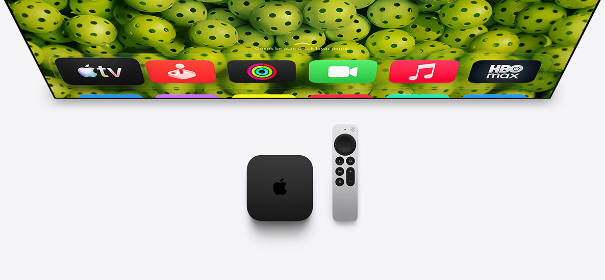 Apple TV 4K dan Siri Remote di bawah layar TV, layar menampilkan ikon aplikasi baris atas Layar Utama di atas latar belakang acar hijau