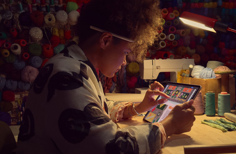 Seseorang sedang duduk sambil memperbesar gambar di layar iPad menggunakan dua jari.