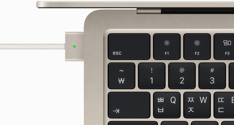 스타라이트 색상 MacBook Air에 연결된 MagSafe 케이블을 위에서 내려다본 모습