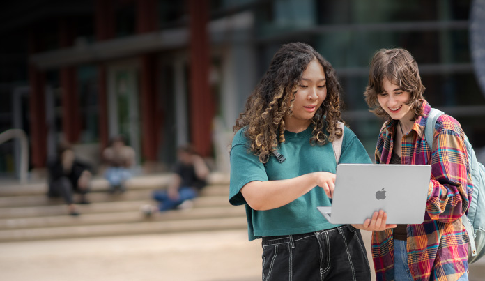 Dos estudiantes universitarios miran la pantalla de una MacBook en el campus