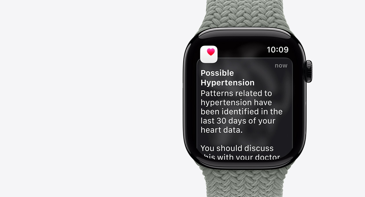 Apple Watch Series 11, natural color, aluminum case, possible hypertension notification, pink heart in white box, right side exterior, Digital Crown, band, green gray Braided Solo Loop