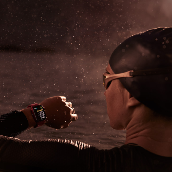 صورة لسبّاح في مسبح ينظر إلى ساعة Apple Watch‏.