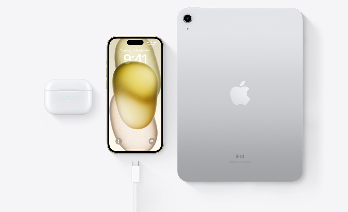 A birds-eye view of AirPods Pro, iPhone 15, and an iPad with a USB-C connector to demonstrate how all three devices can be charged using the same USB-C cable.