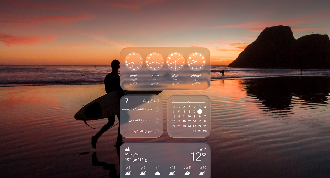 أدوات الساعة والتقويم والتذكيرات والطقس تظهر بتصميم Liquid Glass على شاشة macOS Tahoe مع صورة لراكب أمواج يمشي عند الشاطئ وقت الغروب في الخلفية