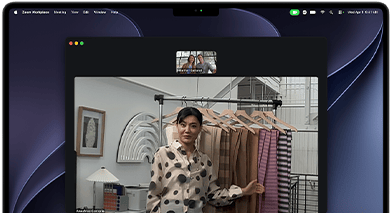 A video call on a MacBook Pro where a woman shows fabrics to two people on the call, with Center Stage keeping her centered in the frame as she moves around