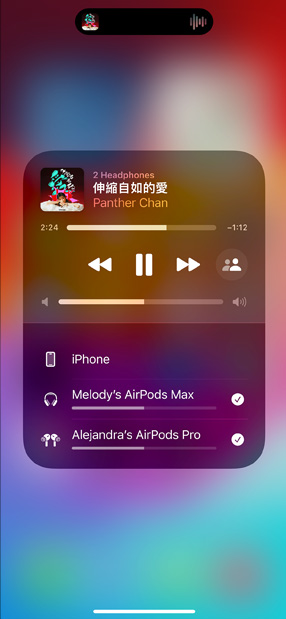 裝有 AirPods Pro 的充電盒旁邊有一部 iPhone，iPhone 連接了兩組 AirPods，每組都有獨立的音量控制。