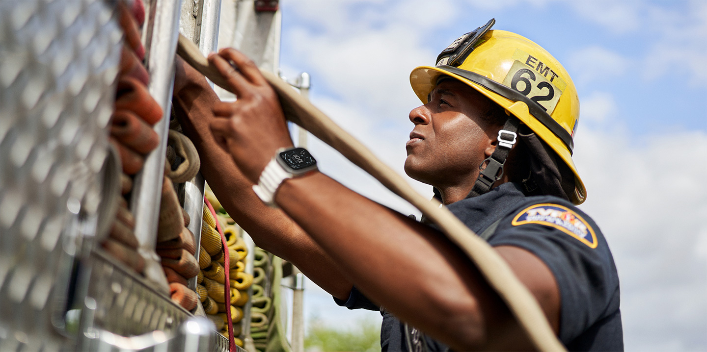 A firefighter pulls a hose out of a fire engine while wearing an Apple&nbsp;Watch