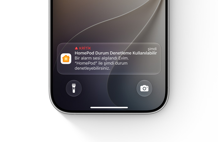 iPhone kilit ekranında Ev uygulaması kritik bildirimi gösteriliyor, metinde şu yazıyor: Kritik, HomePod Durum Denetleme Kullanılabilir, Bir alarm sesi algılandı (THE DOJO), Mutfak HomePod’u ile şimdi durum denetleyebilirsiniz