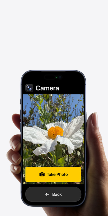 iPhone 17 Pro-scherm met vereenvoudigde interface van de Camera-app met een witte bloem in het frame, de knop Maak Foto en de knop Terug eronder