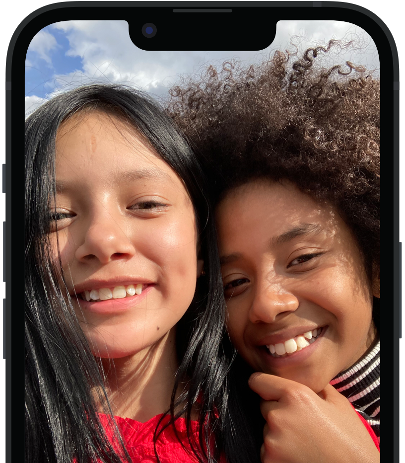 VoiceOver จะอธิบายภาพบน iPhone และแสดงข้อความตามเสียงพูด คนสองคนกำลังยิ้มและโพสท่าถ่ายรูป