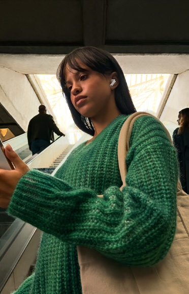 Una persona está mirando su iPhone con los AirPods Pro 3 puestos