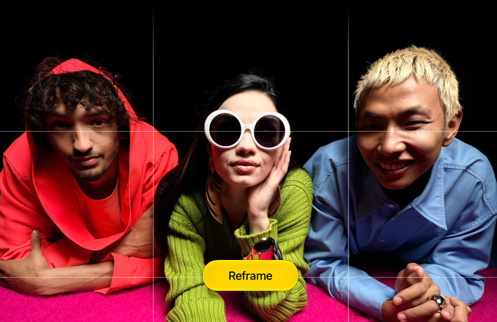 Brightly hued close-up photo of three people leaning forwards over a pink surface, a grid appears over it, along with a button that reads: Reframe