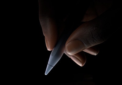 Utilizador a segurar a parte inferior do Apple Pencil Pro entre o polegar e o indicador, em posição de escrita.