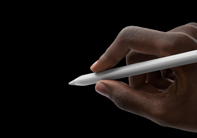Mão a segurar o Apple Pencil Pro em posição de escrita. A ponta está virada para uma interface a mostrar a nova paleta de ferramentas.