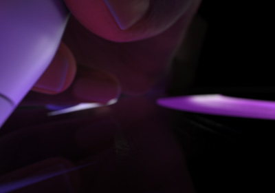 用户以書寫姿勢手執 Apple Pencil Pro。筆尖輕按在顯示器上，繪畫出紫色鮮明的粗線條。