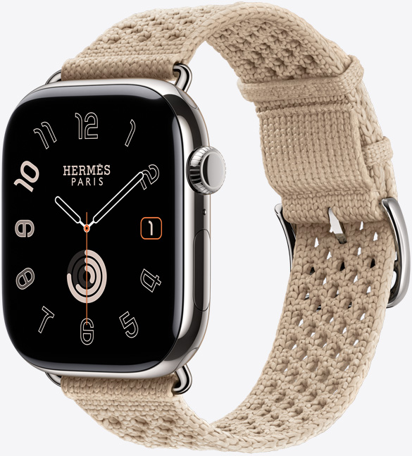 Apple Watch Hermès Series 11, titanium case, silver colour, polished finish, edge-to-edge display, rounded corners, right side exterior, Digital Crown, microphone, side button, analog watch face (hour, minute, second hands), paired with Néo Tricot band, argile colour (beige), knit polyamide yarn material, adjustment holes centred, silver colour buckle and hardware
