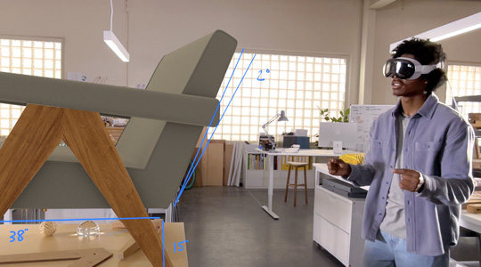 Ein Designer, der die Apple Vision Pro trägt, misst eine 3D Projektion eines Stuhls und dreht den Stuhl mit einer Finger-zusammendrücken-Geste seiner Hände