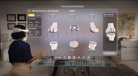 Eine Chirurgin, die die Apple Vision Pro trägt, interagiert mit einer 3D Projektion von Knieknochen und -gelenken, an denen Metallteile angebracht sind