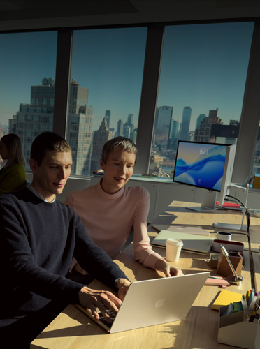 Duas pessoas colaboram em um MacBook Air no escritório, destacando como o MacBook&nbsp;Air é o notebook líder para empresas