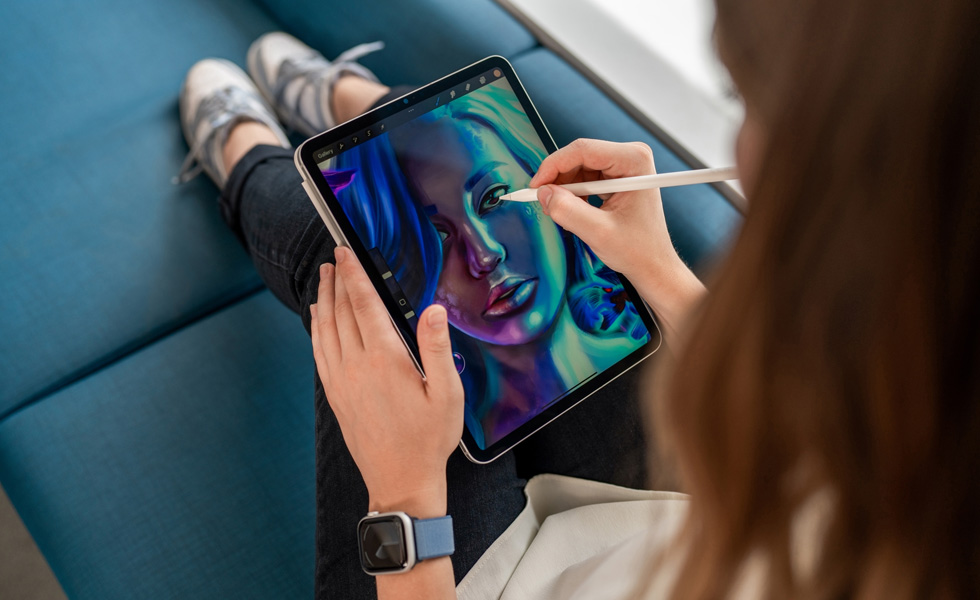 Una studentessa che tiene un iPad sulle gambe mentre usa un’Apple Pencil per disegnare nell’app Procreate