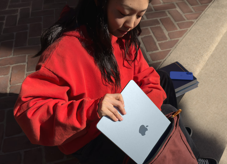 돌계단에 앉아 백팩 안에 MacBook을 집어넣는 사람의 모습.