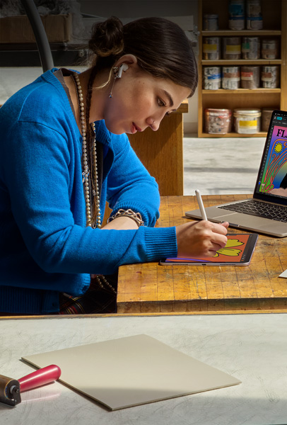 Une étudiante assise à un bureau dessine sur un iPad avec l’Apple Pencil