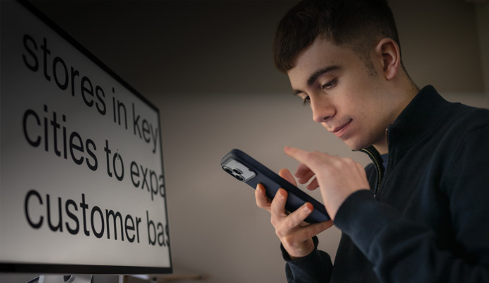 Un étudiant interagit avec son iPhone, qu’il tient à proximité de son visage