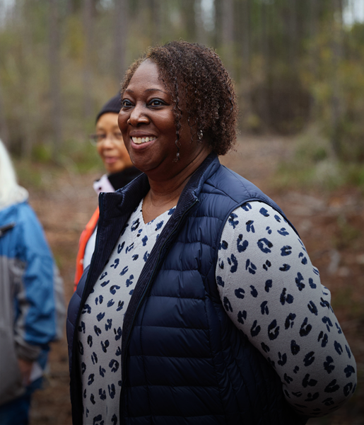 Una mujer negra sonríe junto a otras personas en un bosque