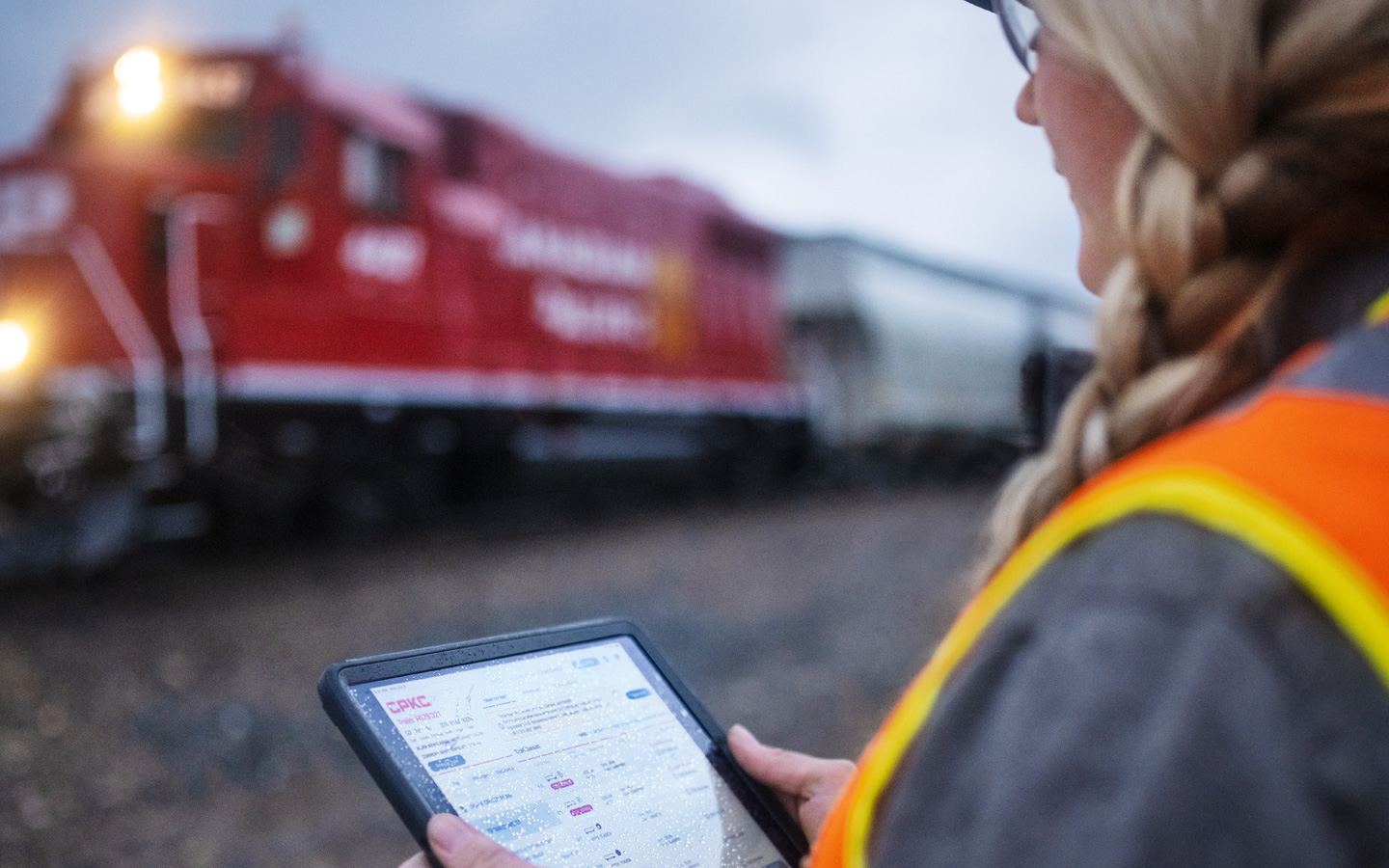 A railroad worker assesses train schedules on iPad while standing in the train depot
