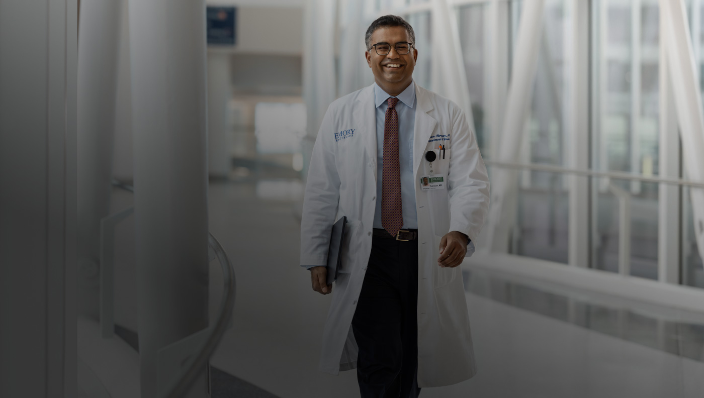 Un médecin qui marche en tenant un MacBook sous son bras droit.