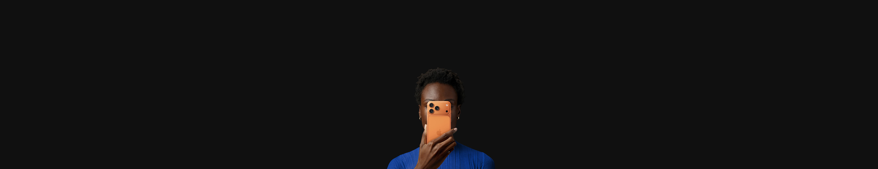 En person holder en iPhone 17 Pro i farven kosmisk orange foran sit ansigt med bagsiden vendt udad.