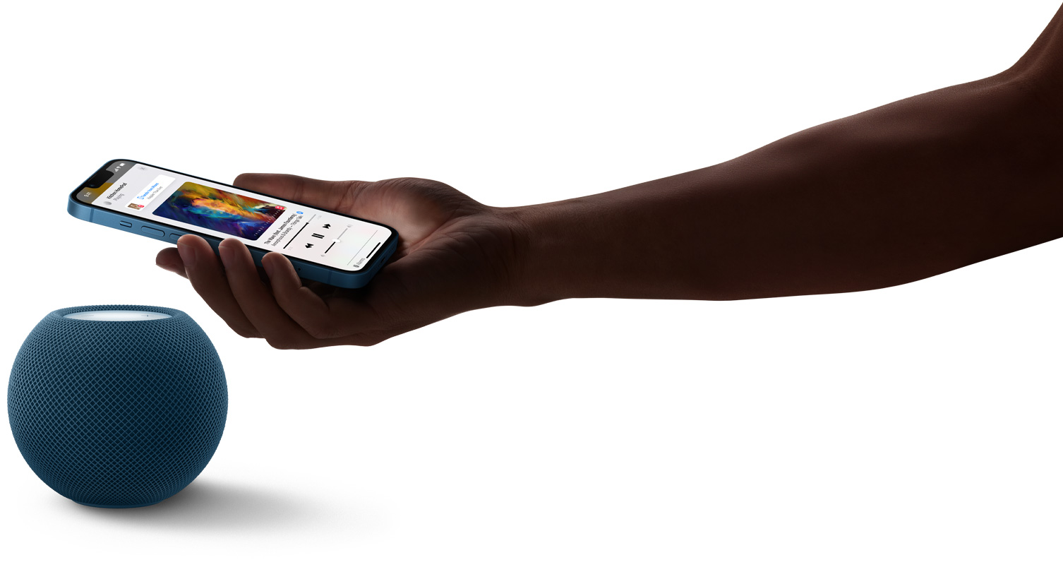 HomePod mini bleu au-dessus duquel la main d’une personne tient un iPhone. L’écran de cet iPhone montre de la musique en cours d’écoute.