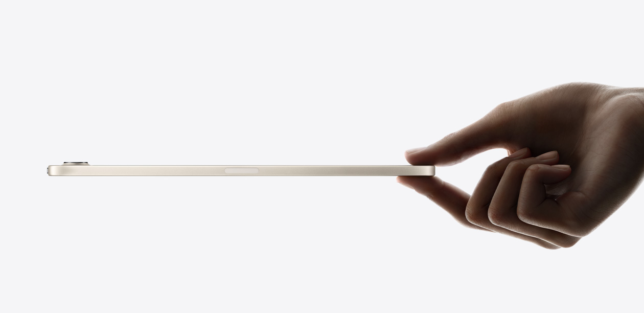 iPad mini, side view in Starlight colour, thin and light design, held in a hand.