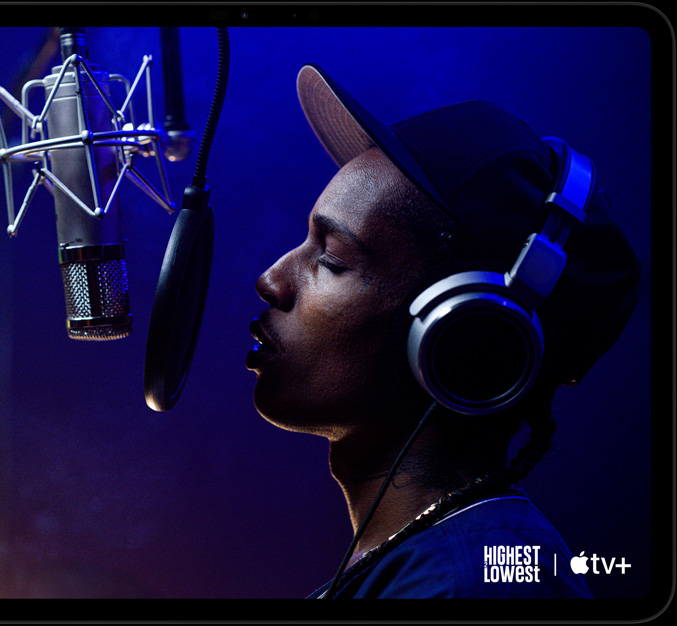 Widoczny od przodu iPad Pro w kolorze gwiezdnej czerni, w układzie poziomym, zaokrąglone rogi, czarna ramka ekranu, na ekranie widać Apple TV+ ze sceną z filmu Apple Original pod tytułem Od góry do dołu, w którym ASAP Rocky jako Yung Felon rapuje do mikrofonu