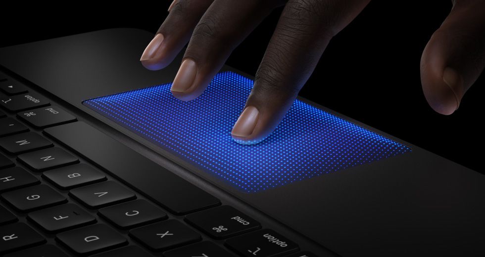 Animation of hand with fingers hovering on Magic Keyboard trackpad, index finger with blue shadow showing tapping action to demonstrate haptic feedback