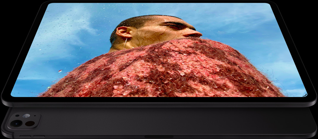 橫向放置的太空黑 iPad Pro 機身正面，展示圓角設計，黑色顯示器邊框，顯示器展示一幅相片，一位身穿紅色毛衣的男人位於藍天下；下方是另一部橫向放置的太空黑 iPad Pro，背面外觀，展示 Pro 相機系統、調高音量按鈕、調低音量按鈕