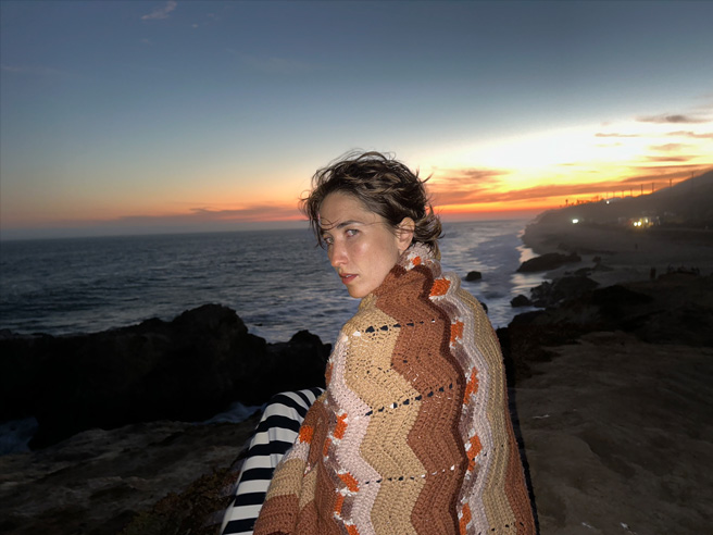 Kayaların üzerinde oturan bir kadının fotoğrafı. Bu fotoğraf yeni Adaptif TrueTone Flash ile çekildi.