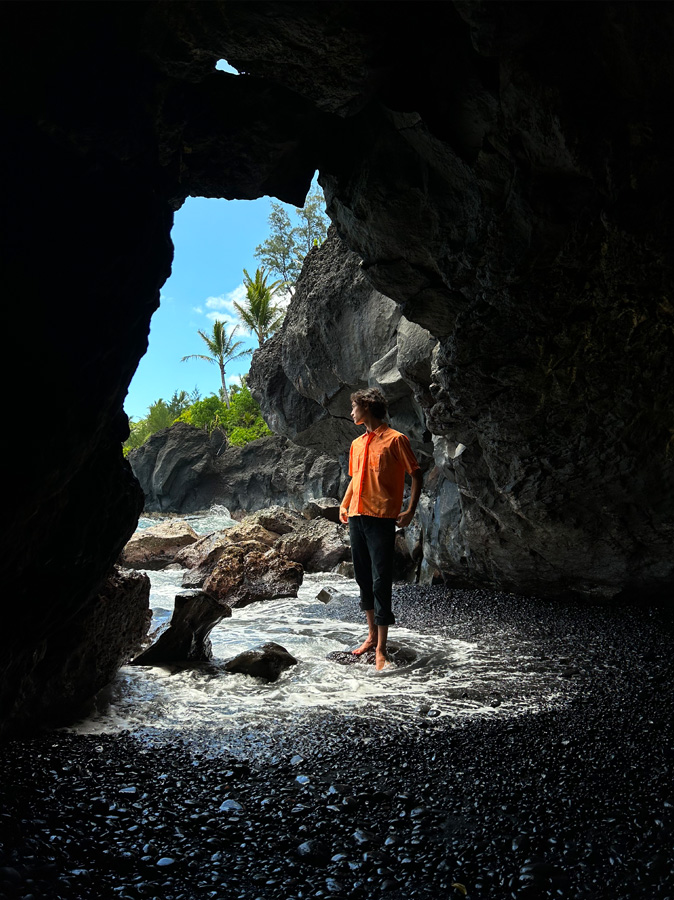 Foto seorang perempuan yang berdiri di pintu masuk sebuah gua, diambil dengan kamera Utama.
