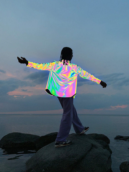 Fotografia de um homem a usar um casaco em tecido metálico iridescente, tirada com o flash True Tone mais brilhante.