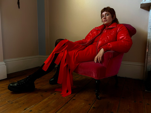 Φωτογραφία ενός ατόμου που κάθεται σε μια καρέκλα σε ένα σκοτεινό δωμάτιο, για να απεικονίσει τις δυνατότητες της κάμερας σε συνθήκες χαμηλού φωτισμού.
