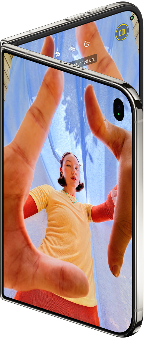 星光白色 iPhone Duo 微微展開，外螢幕展示相機 app 和 Center Stage 前置相機