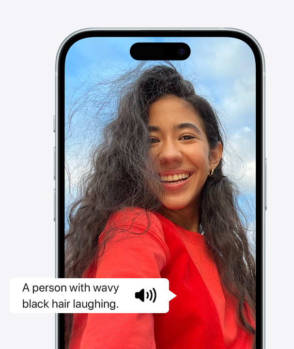 صورة لجهاز iPhone يستخدم ميزة التعليق الصوتي لوصف تفاصيل شخص على الشاشة يضحك وله شعر مموج.