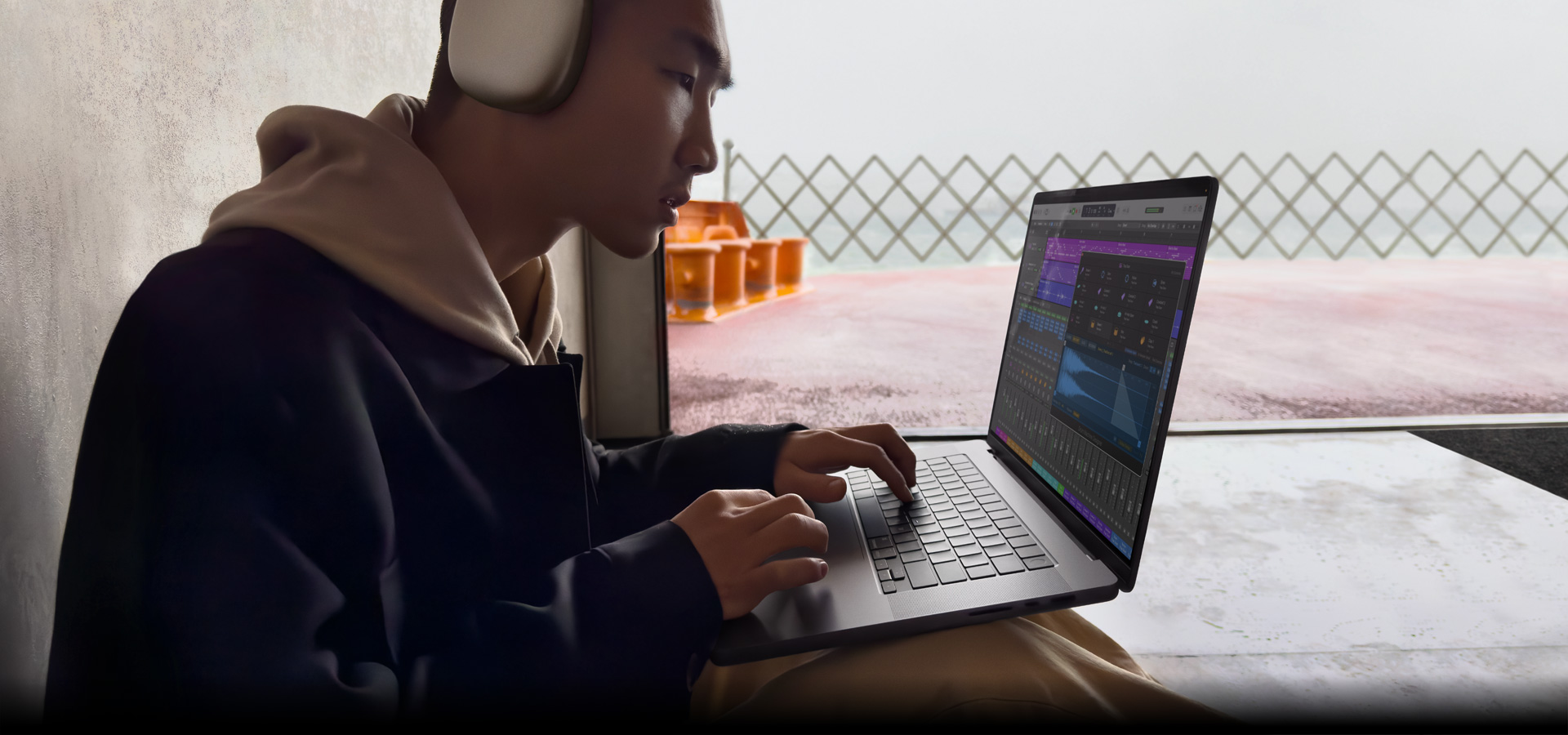 Imagen de perfil de una persona con unos AirPods Max con Logic Pro en un MacBook Pro de 16 pulgadas, la pantalla muestra el espacio de trabajo de Logic Pro