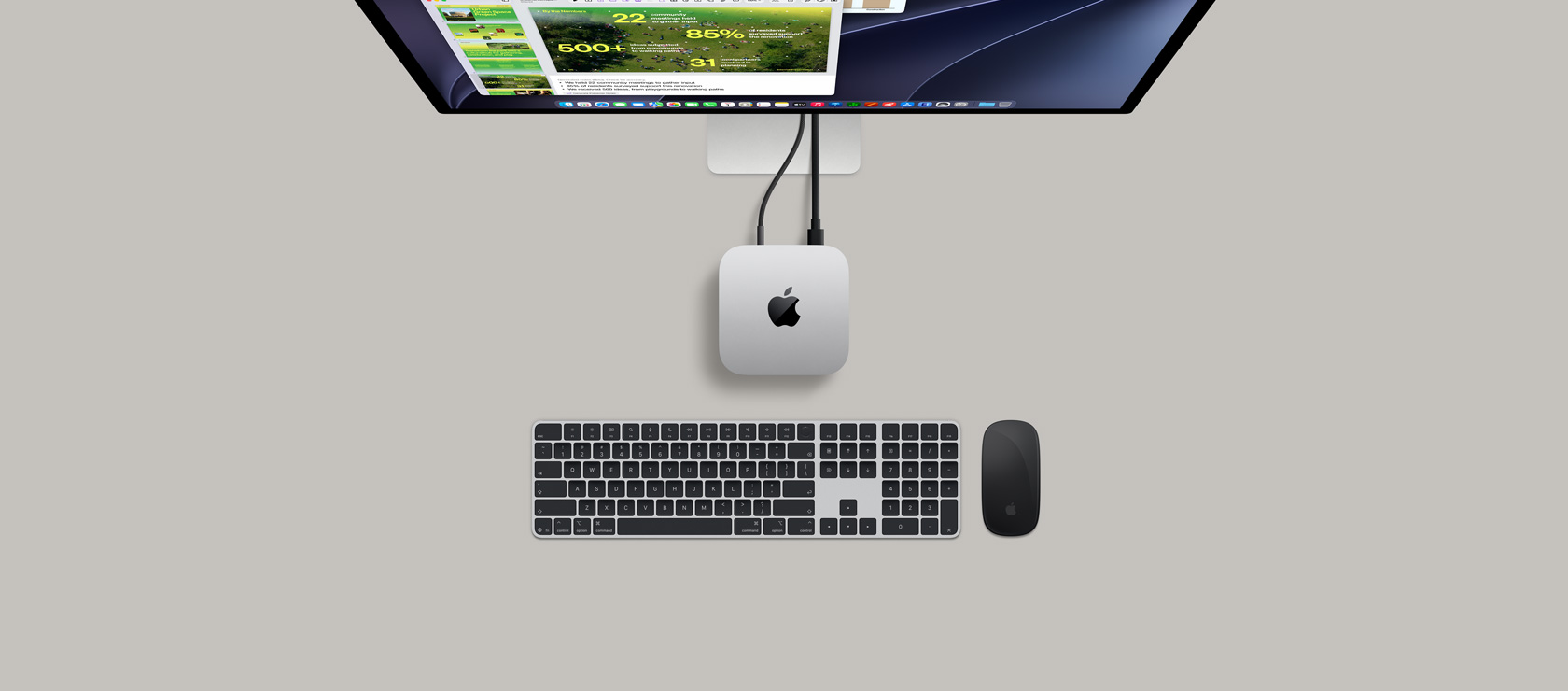 Mac mini, top, silver aluminium, rounded corners, glossy black Apple logo centred, connected by cord, Studio Display partially visible on top with screen showing Calendar app, Keynote presentation, and bar graph open, Magic Keyboard with Numeric Keypad, Magic Mouse visible below Mac mini