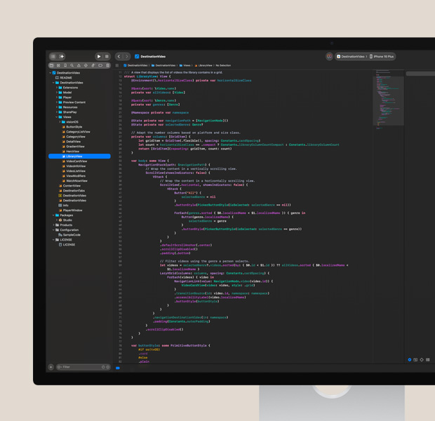 Studio Display screen, Xcode app open with colourful code editor, iPhone with app test partially visible on right side
