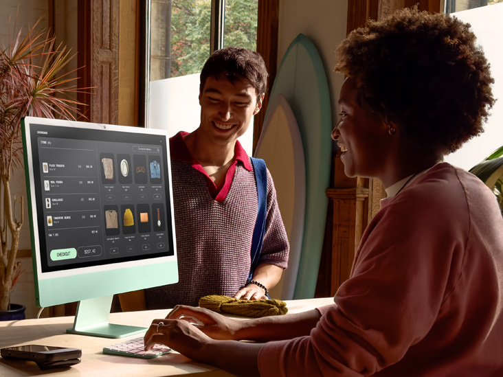 Deux personnes dans une pièce bien éclairée. L’une passe une commande sur un iMac M4 vert.